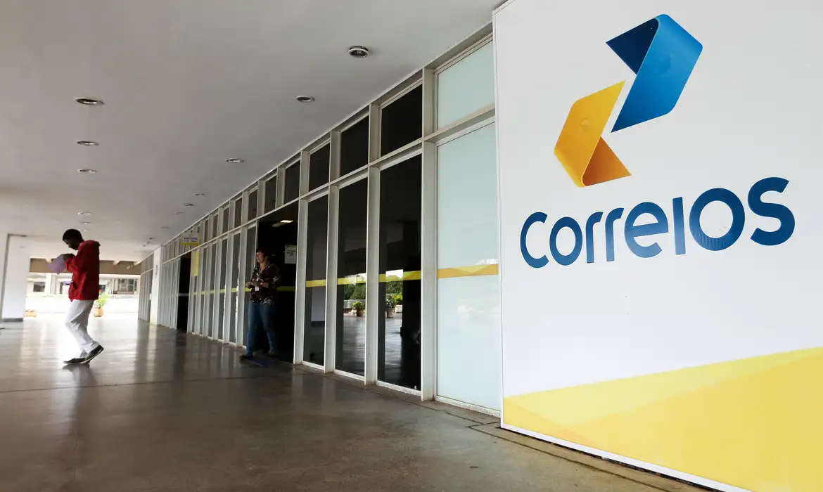 Homem em frente a uma agência dos Correios