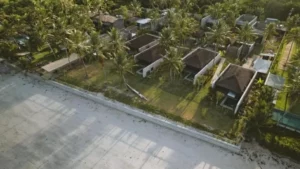 Faixa de areia com casas e vegetação ao fundo
