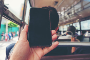 Homem usa telefone celular em ônibus
