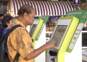 Idoso faz check-in em terminal de autoatendimento em aeroporto