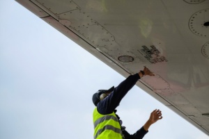 homem com protetores de ouvido consertando asa de avião