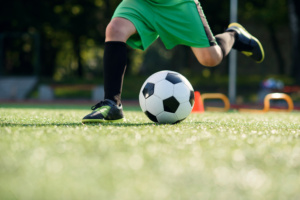 Criança / adolescente jogando futebol