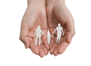 Mãos segurando papel recortado em formato de família composta por mãe, pai e filho