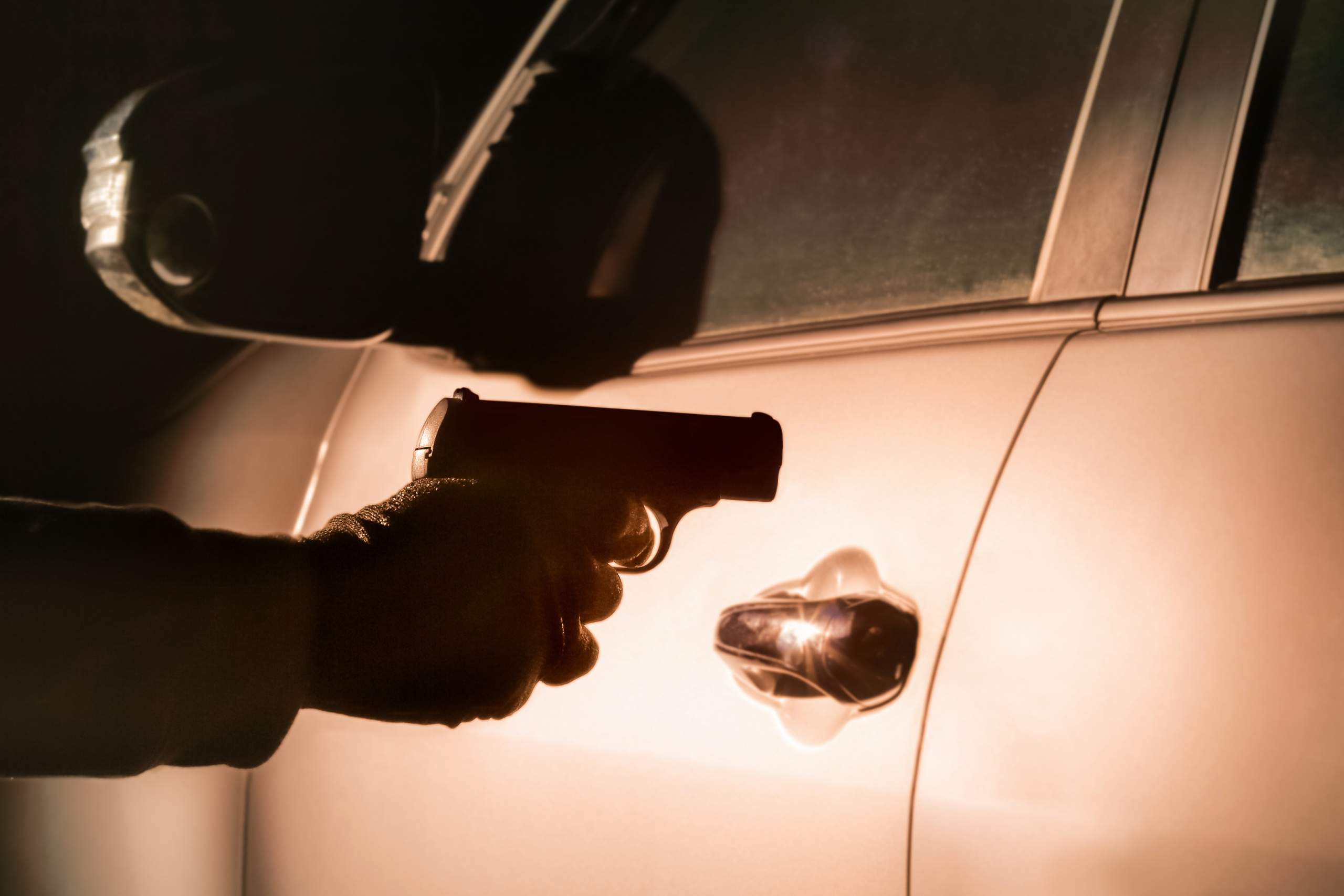 carro e sombra de homem com arma