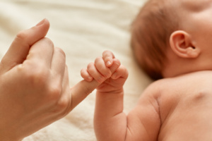 bebê segura dedo da mãe