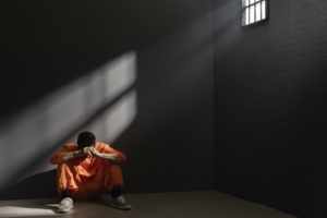 Homem sentado no chão na cadeia