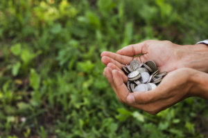 Mãos em concha segurando amontoado de moedas