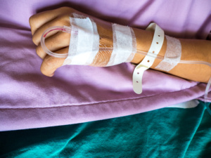 mão com acesso às veias, em cama de hospital
