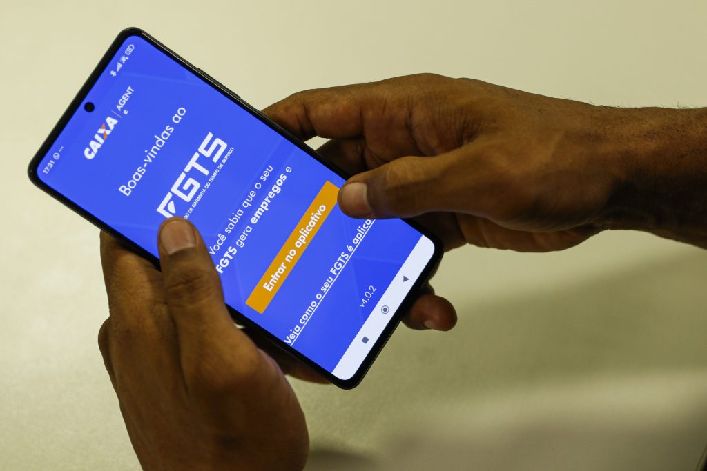 homem segurando celular que mostra aplicativo do FGTS