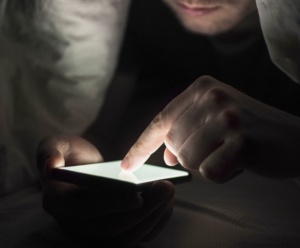 homem no escuro mexendo no celular