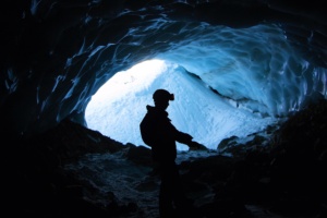Homem dentro de caverna azulada, contra a luz