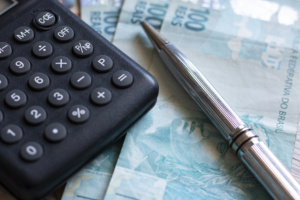 calculadora, caneta e notas de 100 reais