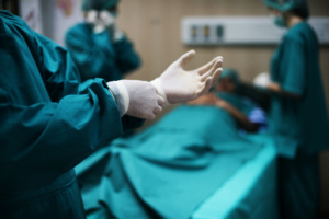 médico pondo luvas em sala de cirurgia