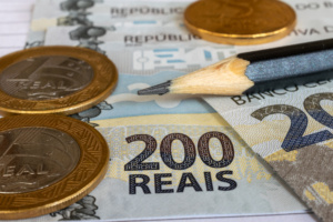 moedas de 1 real, notas de 200 reais, lápis
