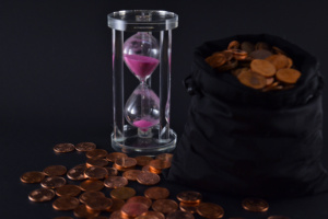 ampulheta com areia rosa, saco de moedas, fundo preto