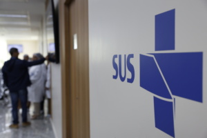 sala em posto de saúde; logo do SUS em primeiro plano