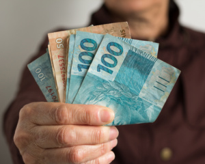 homem mostrando notas de 100 e 50 reais