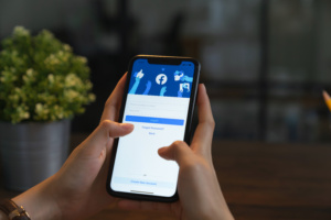 pessoa mexendo em celular, que mostra facebook na tela